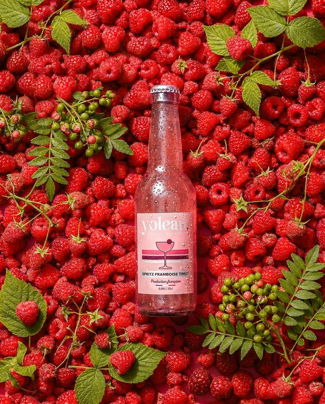Baies de poivre de Timut et framboises fraîches à côté d'une bouteille de Spritz Framboise Timut Yoleau