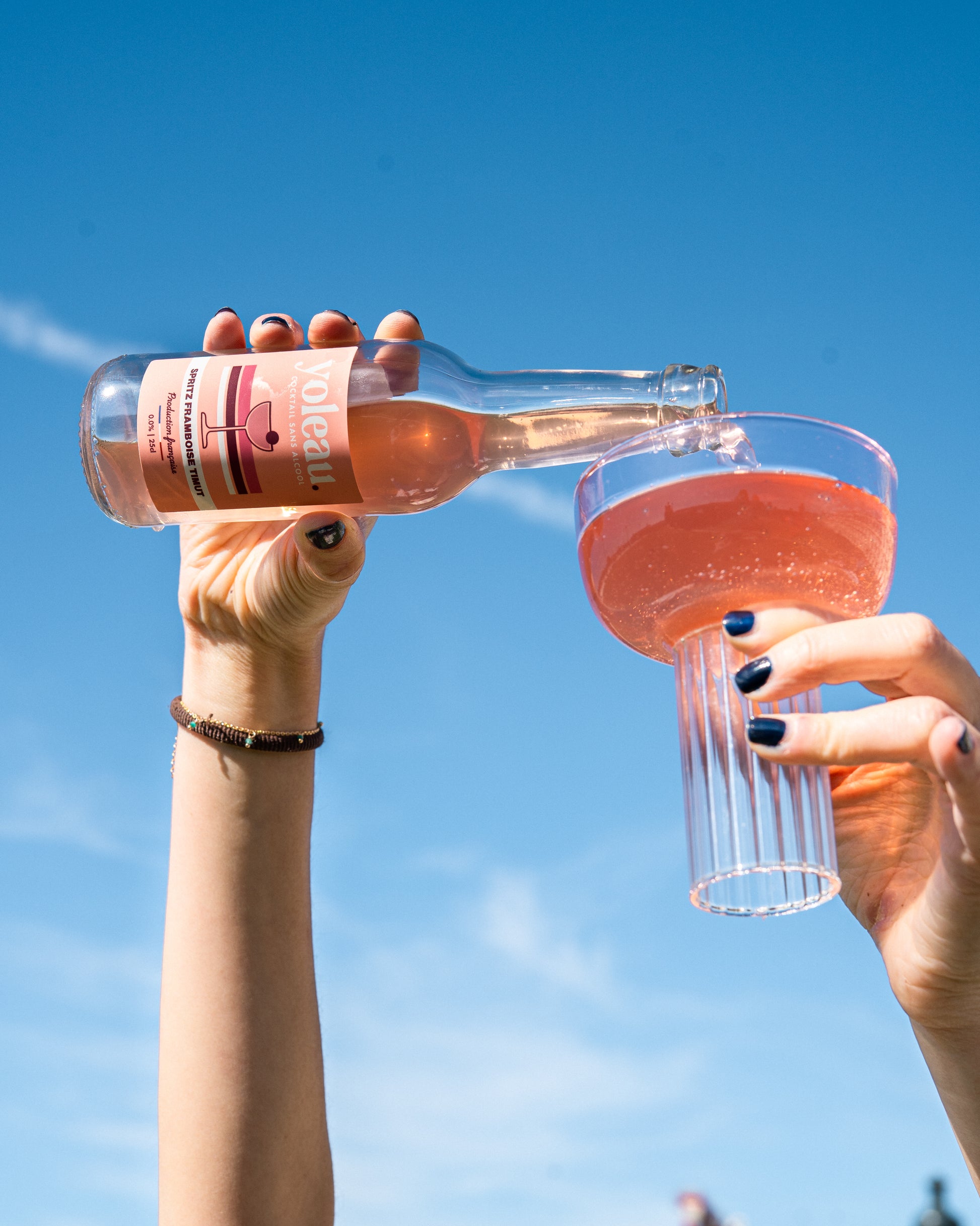Spritz Framboise Timut Yoleau, servi dans verre à cocktail, ciel bleu